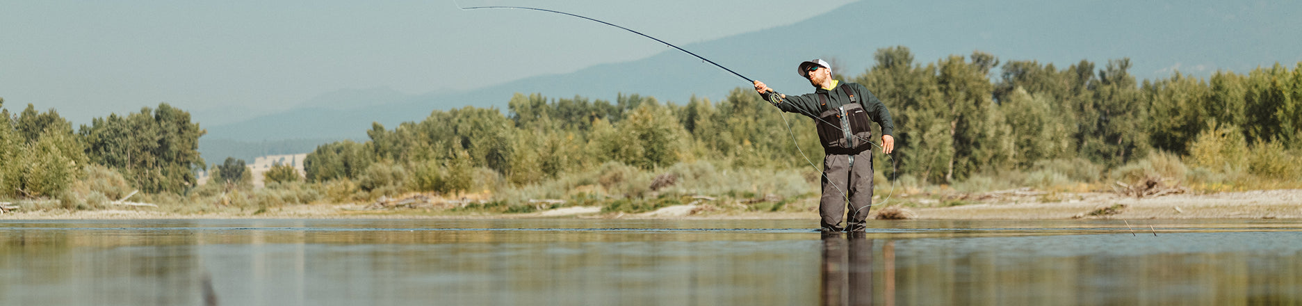 Angler cast rod wearing Grundens waders