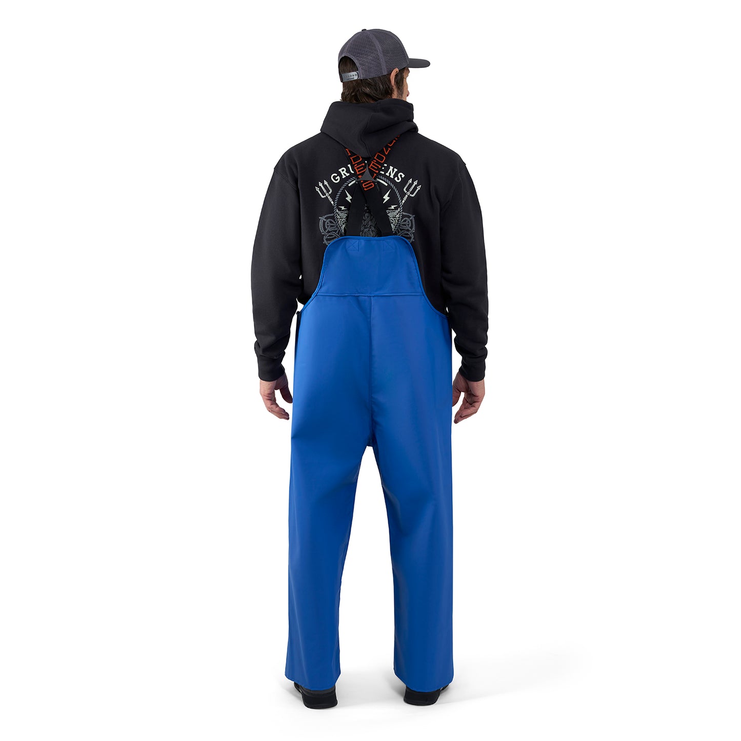 Man wearing blue bib overalls with adjustable straps, standing with his back to the camera.