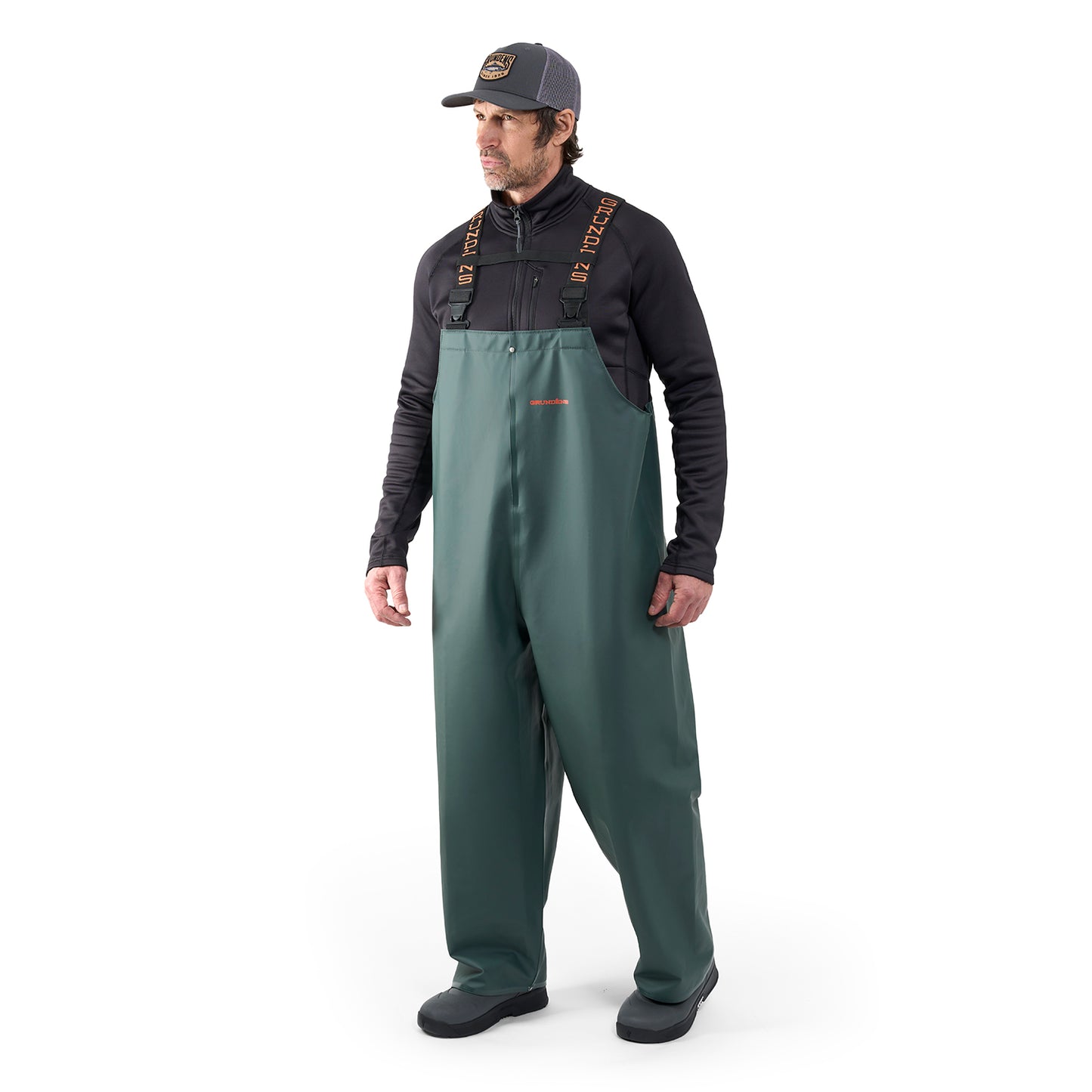 Man wearing green waterproof bib overalls with adjustable straps and a black long-sleeve shirt underneath.