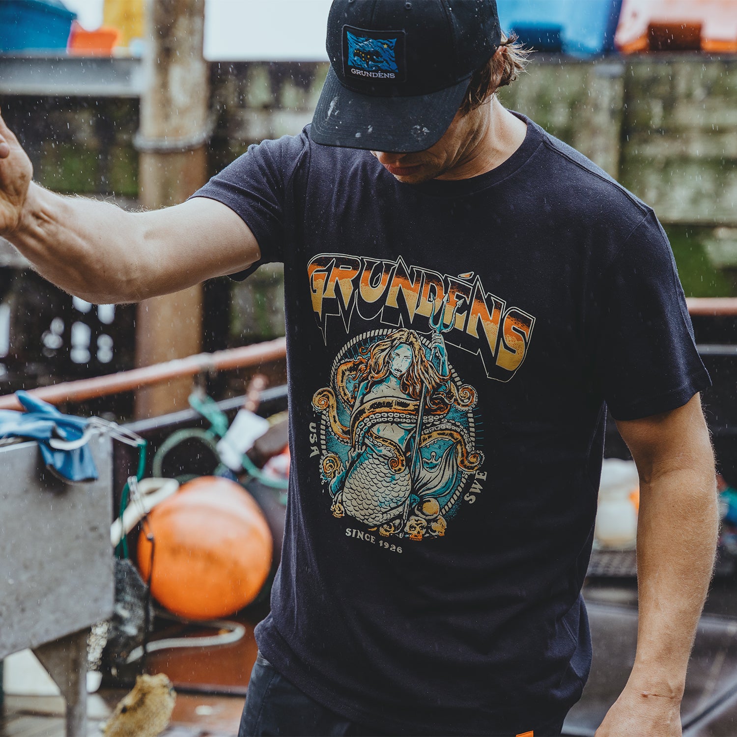 Black t-shirt featuring a colorful mermaid graphic and the brand name "Grundéns" on the front.