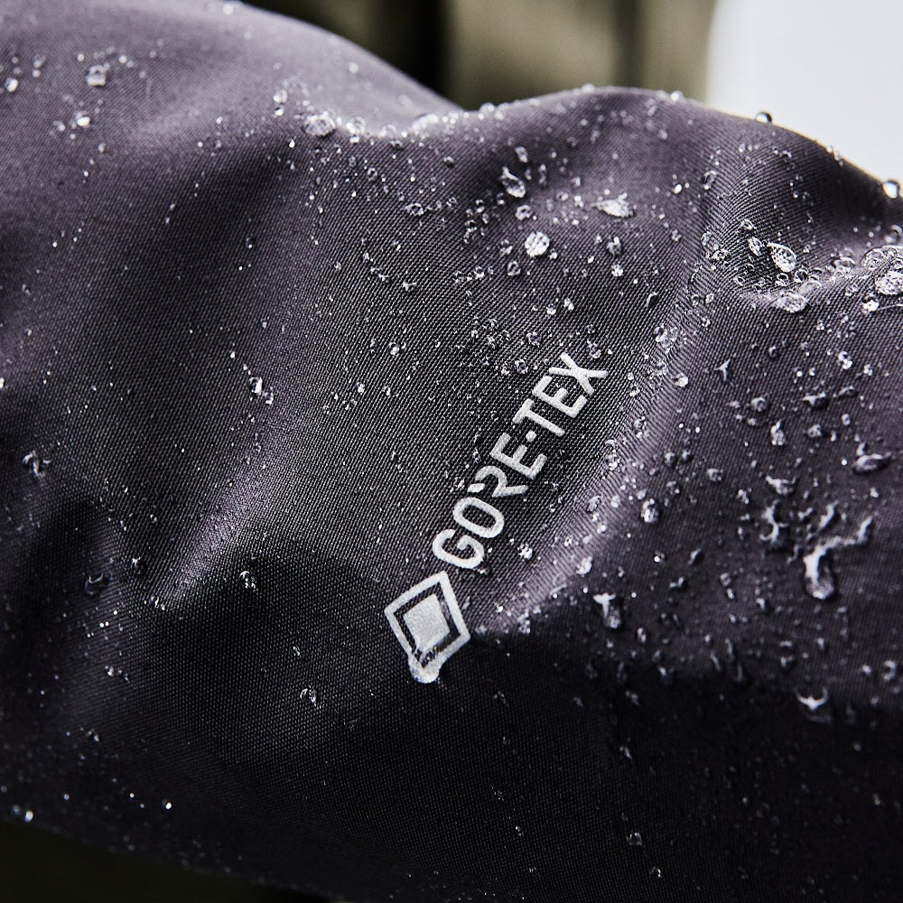 Close-up of a black fabric with water droplets and a visible GORE-TEX® logo.